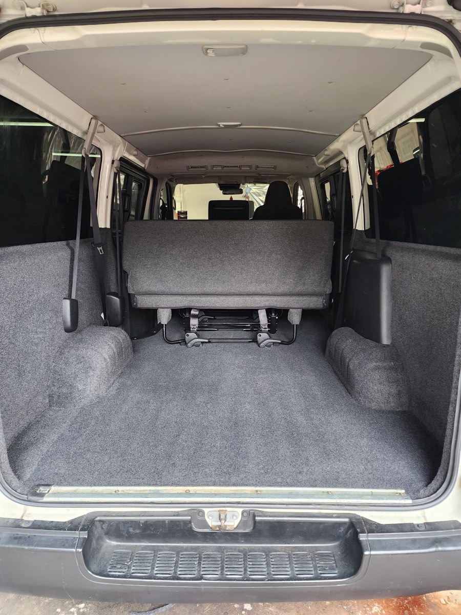 Toyota Hiace cargo van after — full grey carpet kit installed across floor, sides, and wheel arches
